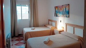 A hotel room with two beds, a ceiling fan, a painting, and a window with curtains. - Nuevas Poblaciones, Despeñaperros (Santa Elena)