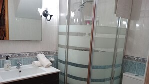 A modern bathroom with a glass-enclosed shower, a white sink with a soap dispenser, and a toilet. - Nuevas Poblaciones, Despeñaperros (Santa Elena)