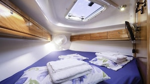 Ein gemütliches Schlafzimmer mit zwei Betten, einem Dachfenster, Holzschränken und einem Ventilator.