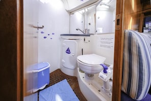 A compact bathroom with a toilet, sink, and storage unit.