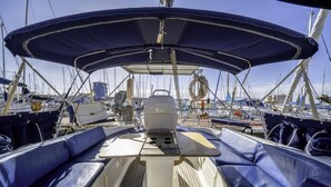 Ein Bootsdeck mit blauen Sitzgelegenheiten, einem zentralen Tisch und einem Sonnendach.