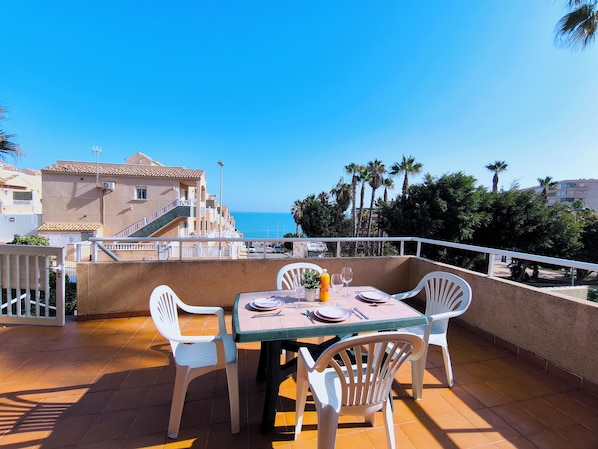 A terrace with a table set for two, overlooking a coastal view. - Sea View Bungalow With Pool (Torrevieja)