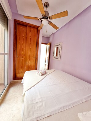 A bedroom with a bed, a ceiling fan, a wooden door, and a window. - Sea View Bungalow With Pool (Torrevieja)