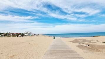 A wooden boardwalk leading to a beach with a clear sky.