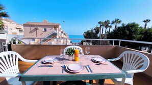 Ein Tisch für zwei Personen mit Blick auf das Meer, weiße Stühle und ein gefliester Boden.