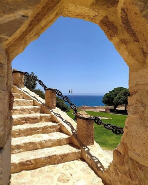 A stone staircase leading to a view of the sea, with a chain barrier and a clear blue sky. - Sea View Bungalow With Pool (Torrevieja)