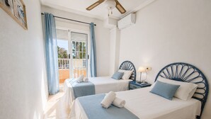 Camera d'albergo con due letti, un balcone, una ventola a soffitto e un condizionatore.
