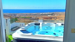 Un bain à remous avec vue sur l’océan et sur les bâtiments d’une ville lointaine.