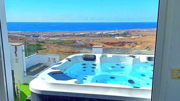 Ein Whirlpool mit Blick auf das Meer und eine entfernte Stadtlandschaft.