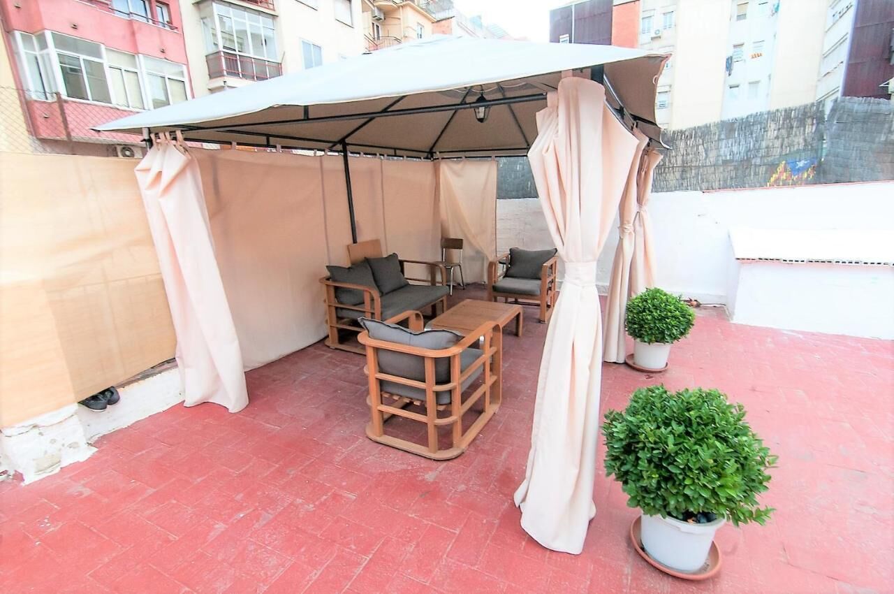 A covered outdoor seating area with a table and chairs, a canopy, and potted plants.
