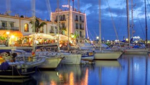 Un port de plaisance avec plusieurs bateaux amarrés, un bâtiment doté d’une tour et un restaurant situé au bord de l’eau.