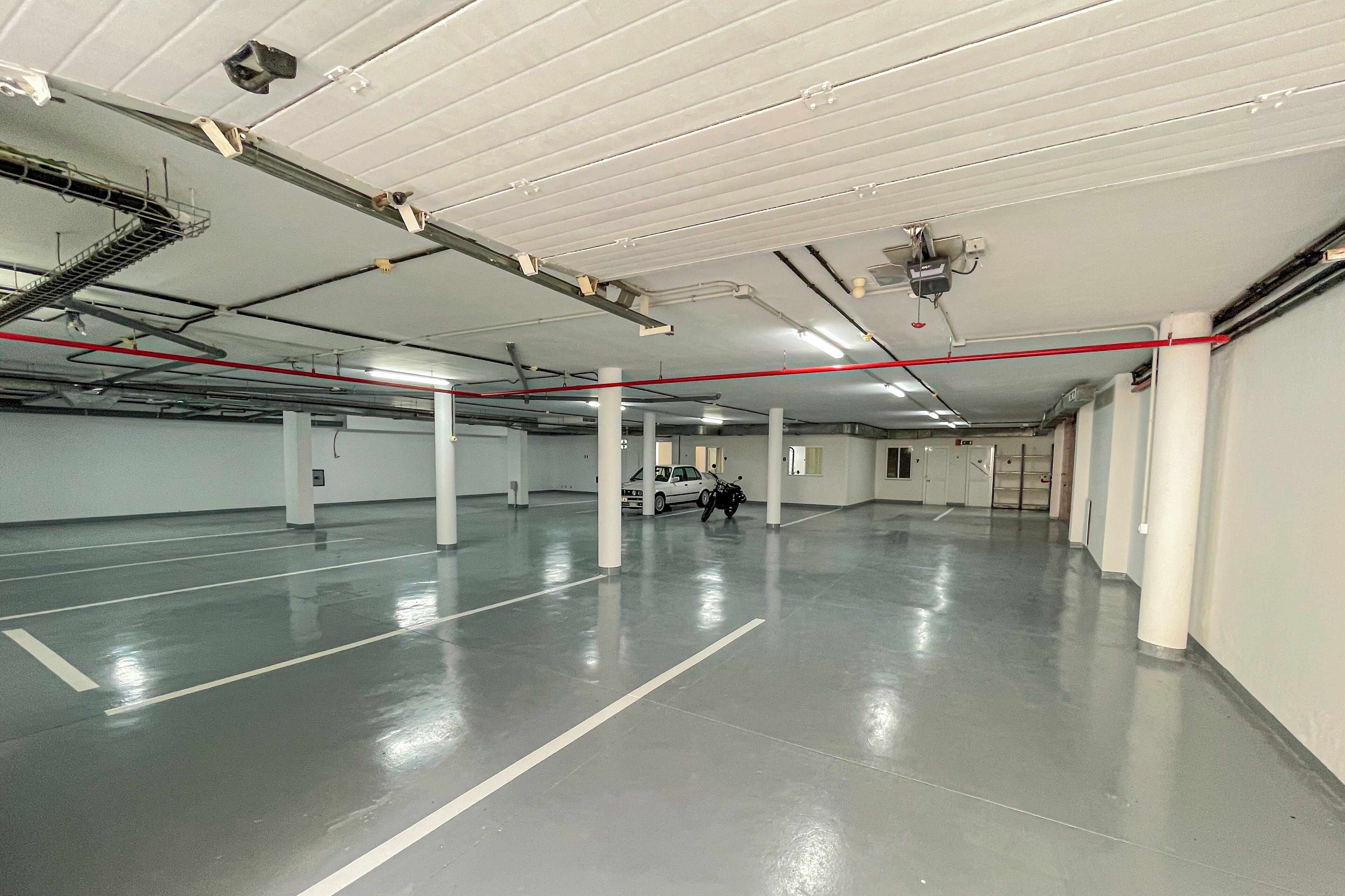 A spacious indoor parking area with a clean, white ceiling and a polished concrete floor.