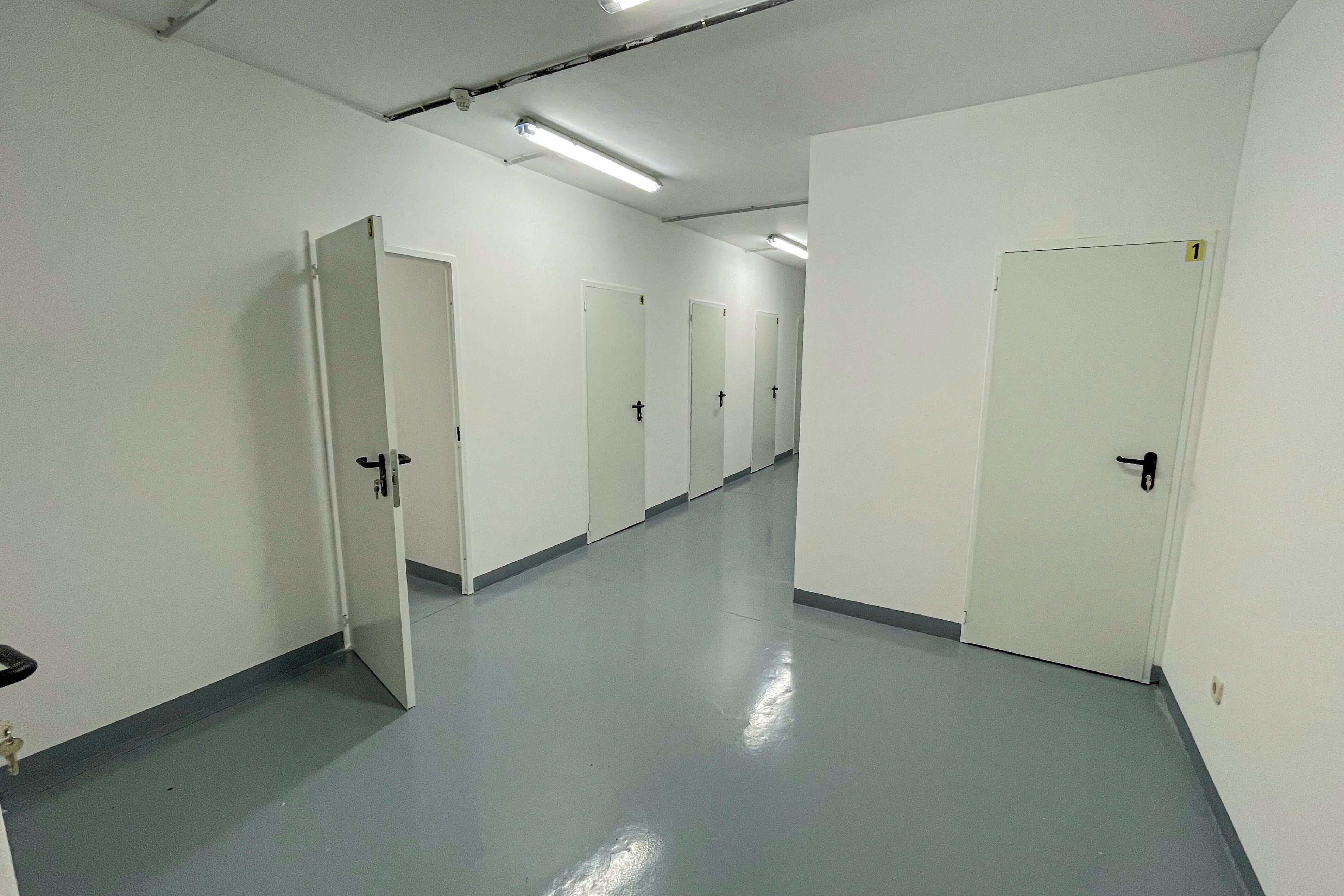 Un couloir avec des portes blanches, chacune étant numérotée.