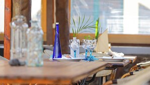 Un tavolo da pranzo apparecchiato con bicchieri di vetro blu e bottiglie trasparenti, con vista su un edificio sullo sfondo.