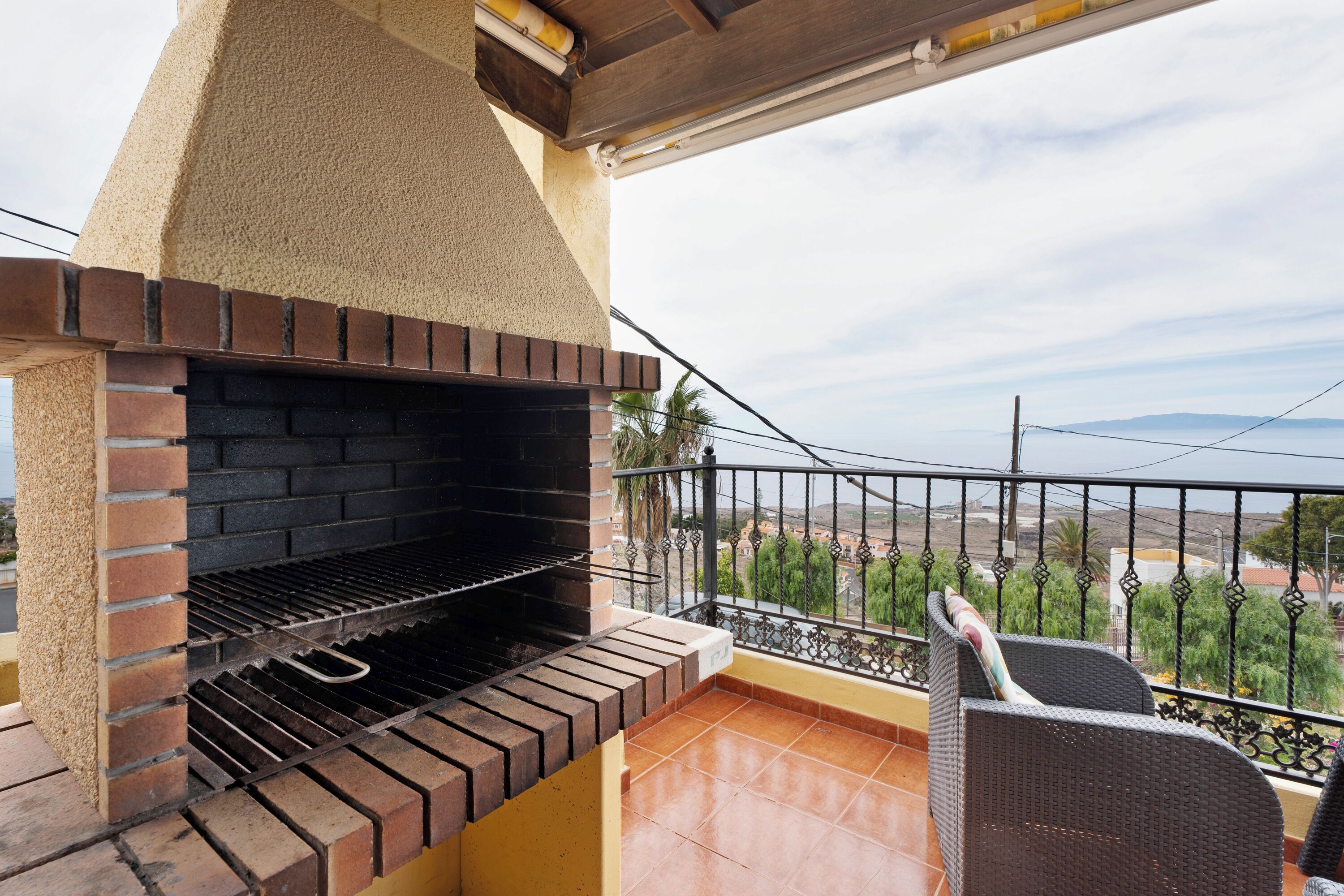 Una parrilla de ladrillo al aire libre en un balcón con vistas a un paisaje urbano.