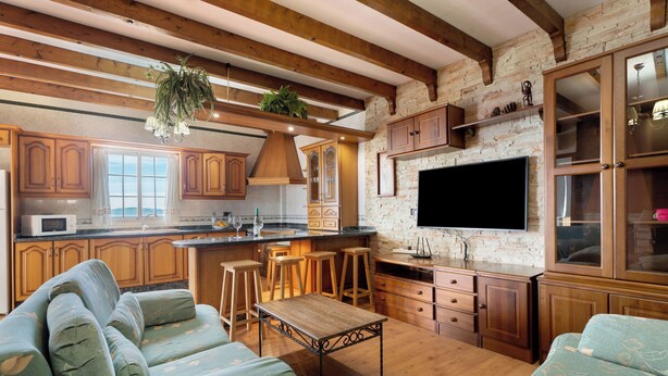 A spacious living area with a large sofa set, a wooden coffee table, and a kitchen with wooden cabinets and a stone wall backdrop. - Rural House Tijoco Bajo & With Jacuzzi Adeje (Adeje)
