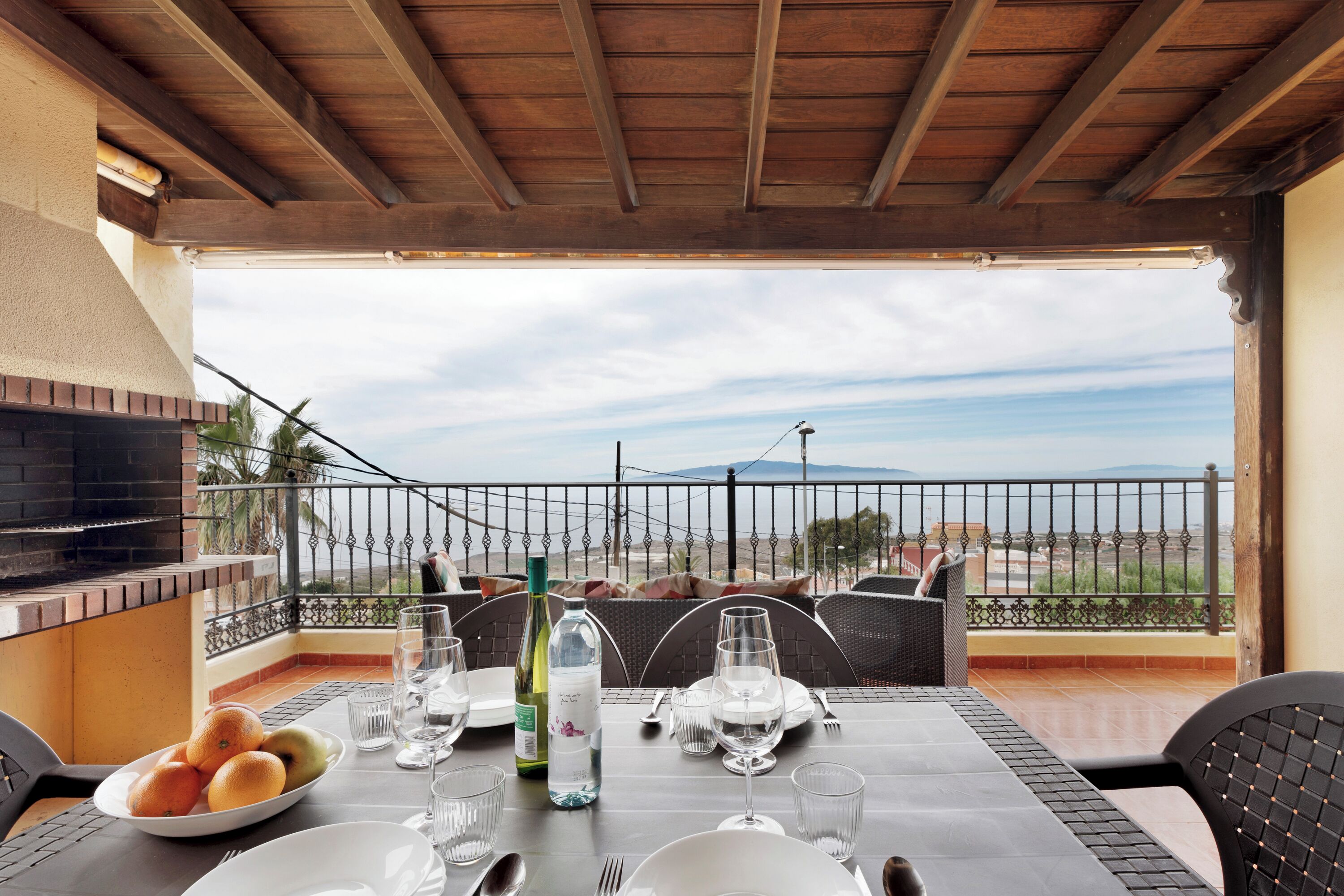 Un comedor con una mesa preparada para dos, una parrilla y vistas al mar.