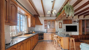 A spacious kitchen with wooden cabinets, a granite countertop, and a central island with bar stools. - Rural House Tijoco Bajo & With Jacuzzi Adeje (Adeje)