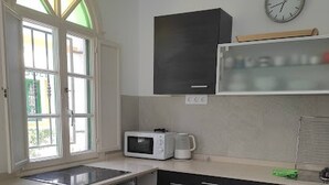 Una cocina compacta con microondas, un lavamanos y una silla.