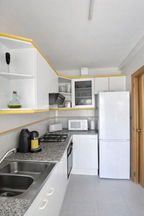 A modern kitchen with white cabinets, a microwave, a stove, and a refrigerator. - Beautiful And Bright Apartment In Calafell, (El Vendrell)