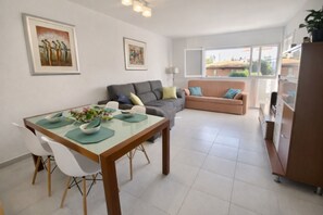 A modern living room with a dining table, sofas, and artwork on the walls. - Beautiful And Bright Apartment In Calafell, (El Vendrell)