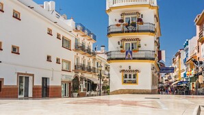 A multi-story building with balconies, a flag, and a clear sky. - Playamar, Torremolinos, Beautiful Apartment by the Sea (Torremolinos)