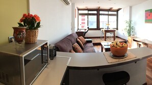 A modern kitchen with a built-in oven, a dining area with a table and chairs, and a large window providing natural light. - Playamar, Torremolinos, Beautiful Apartment by the Sea (Torremolinos)