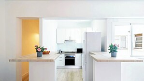 A modern kitchen with white cabinets, a built-in oven, and a refrigerator. There are potted plants on the countertops. - City Loft Santa Cruz (Santa Cruz de Tenerife)