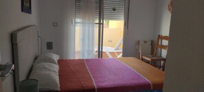 Une chambre à coucher avec un lit, une chaise, une lampe et une vue sur l’extérieur.