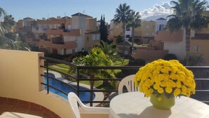 Ein Balkon mit Pool, einem weißen Tisch und einer Vase mit gelben Blumen.
