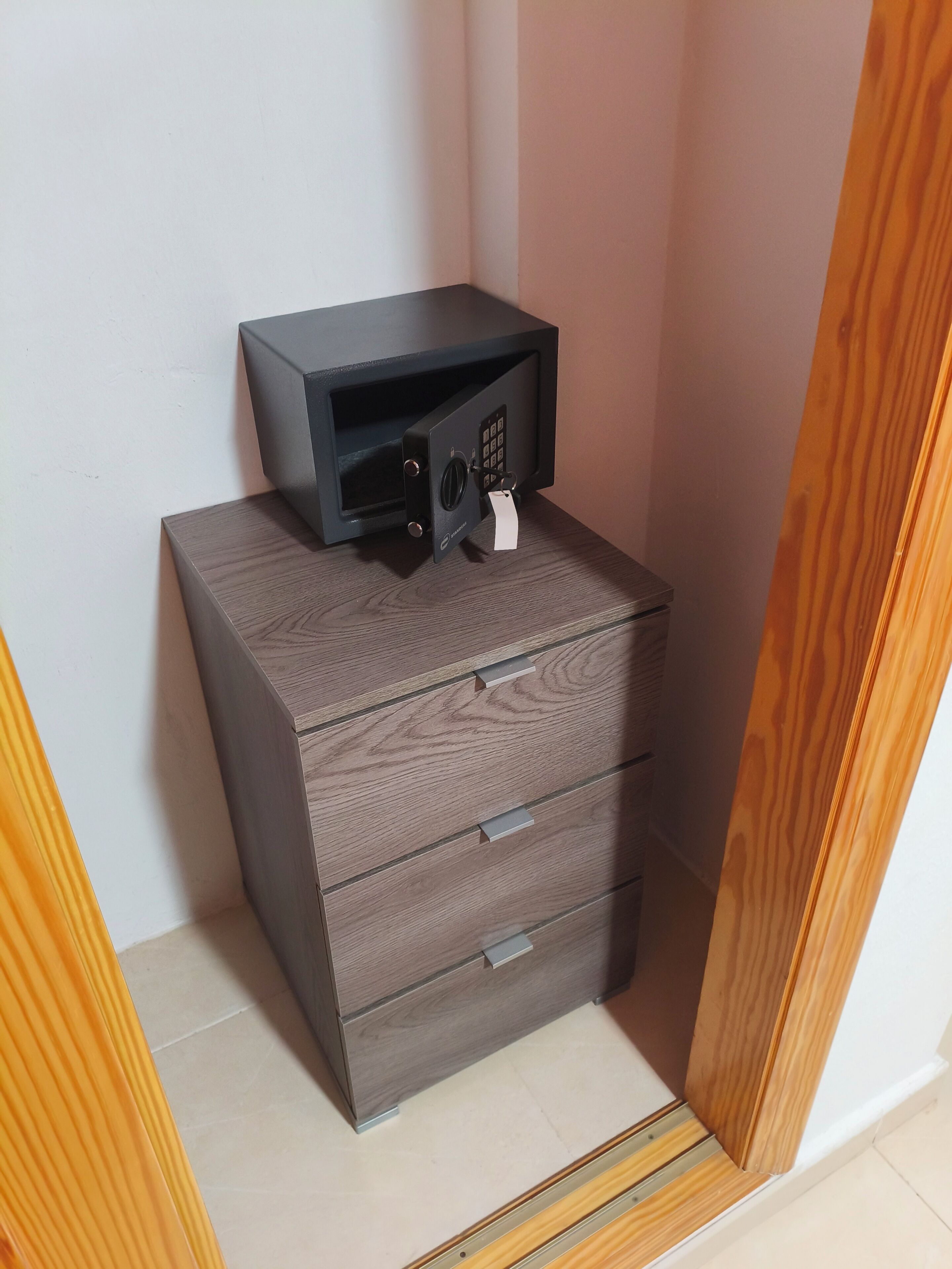 Un petit meuble en bois de couleur sombre, sur lequel est posé un four à micro-ondes noir.