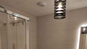 Un baño moderno con cabina de ducha de vidrio, un bidé, un inodoro y un mueble de tocador de madera con espejo.