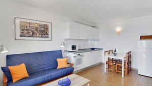 A compact living space with a sofa, a dining table, and a kitchenette. - Costa Isora First Line and Pool (Guia de Isora)