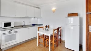 A compact kitchen with white cabinets, a microwave, a sink, a stove, and a refrigerator. - Costa Isora First Line and Pool (Guia de Isora)