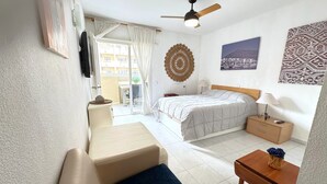 Una camera d'albergo con un letto, una scrivania, una sedia, una ventola a soffitto e vista all'esterno.