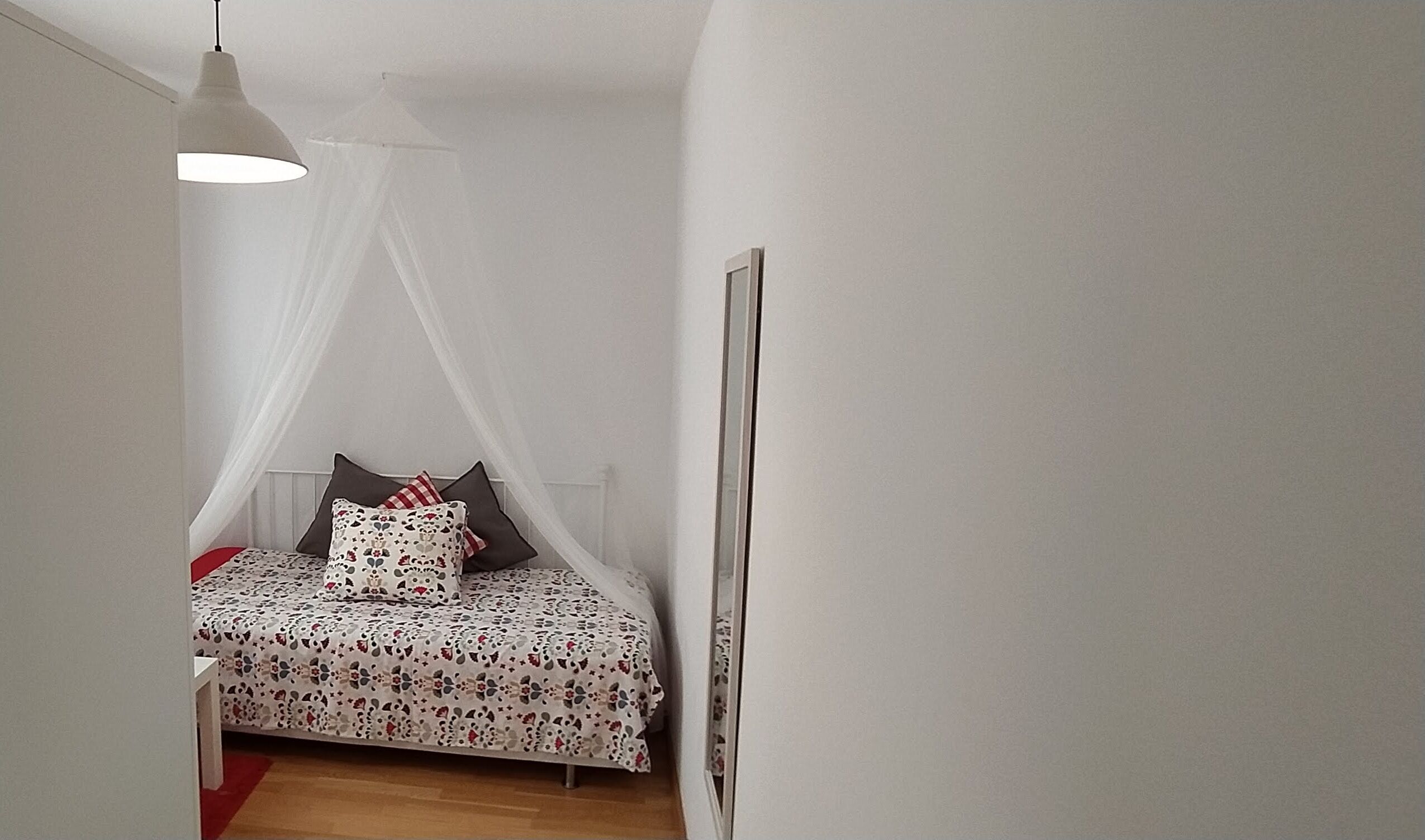 A bedroom with a bed, a canopy, a bedside table, and a wall-mounted picture.