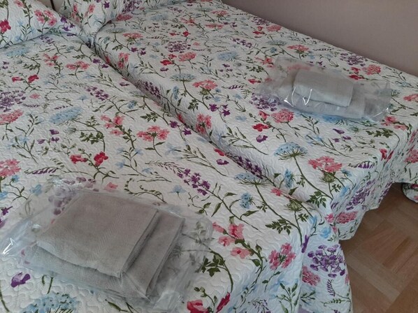 A bed with floral bedding and a neatly folded blanket on the side.