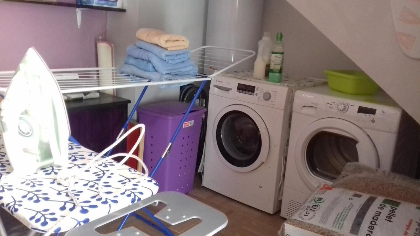 A laundry area with a washing machine, dryer, iron, and stacked towels.