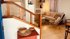 A staircase with wooden railings leading to a living room with a sofa, armchair, and a small table with baskets. - Casa Paca - Your Private Oasis in Lanzarote - Paradise by the Sea (Yaiza)