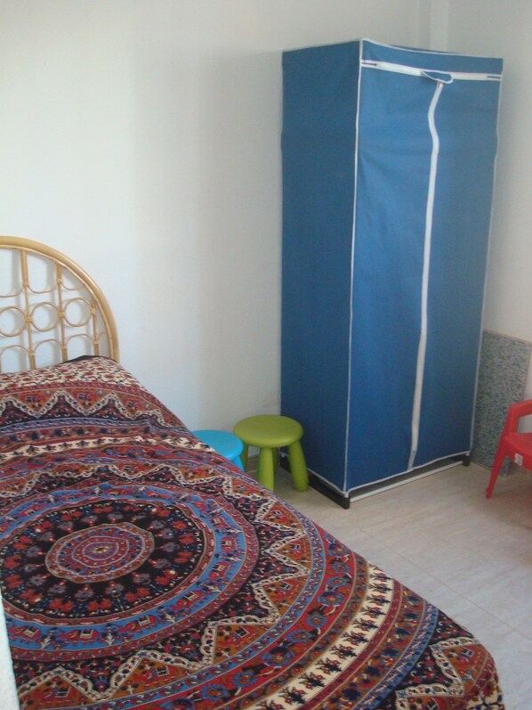 Une chambre à coucher avec un lit, une armoire et un tabouret.