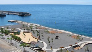 Μια παραλιακή λεωφόρος με μια καμπυλωτή πεζοδρομημένη διαδρομή, χώρους για καθιστικό και μια προβλήτα που εκτείνεται προς τη θάλασσα.