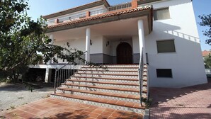 Ένα διώροφο κτίριο με λευκή πρόσοψη, κεραμοσκεπή και μπαλκόνι.