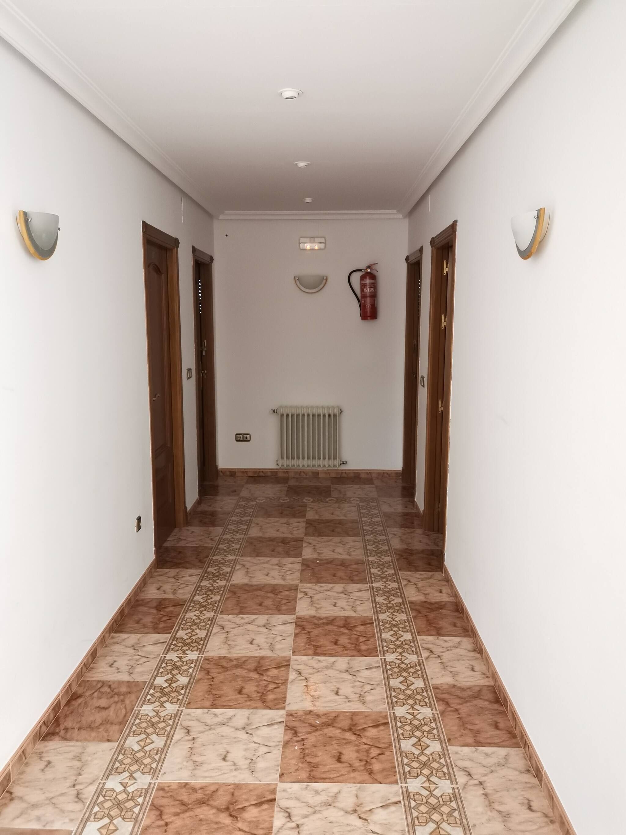 A hallway with patterned tiles, wooden doors, and a radiator.