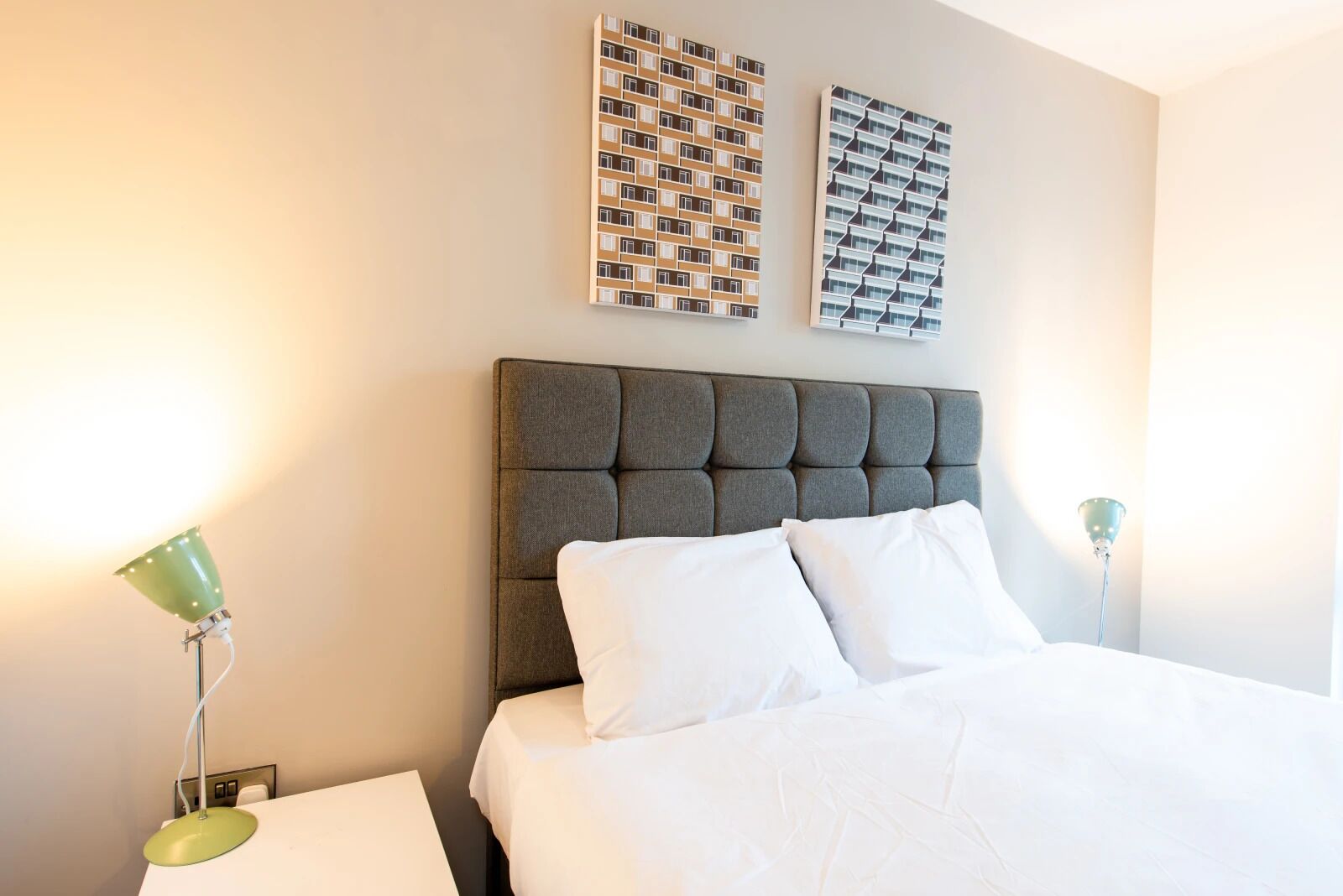 A hotel room with a large bed, two nightstands, and two wall-mounted lamps.