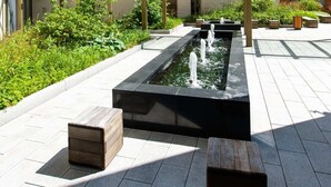 A courtyard with a rectangular water feature, seating areas, and a glass pergola. - The Assembly (Manchester)