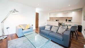 A modern living room with a glass coffee table, a sofa, and a dining area with a glass table and chairs. - The Assembly (Manchester)
