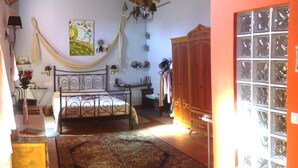 Un dormitorio con cama, armario, ventana y una silla colgante.