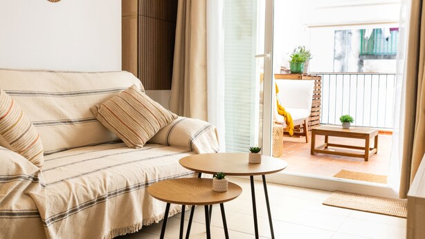 A living room with a sofa, two small tables, and a view of the outside balcony. - Terrace Retreat -stay in the Heart of Sitges (Sitges)