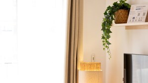 A modern living room with a wooden table, a yellow chair, a flat-screen TV, a lamp, and a plant. - Terrace Retreat -stay in the Heart of Sitges (Sitges)