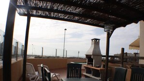 A rooftop terrace with a table and chairs, a grill, and a view of the cityscape. - Bravo´s Aparment Cotillo 1 (La Oliva)